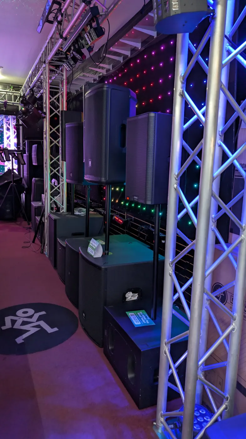 Powered speakers on stands under the lighting truss