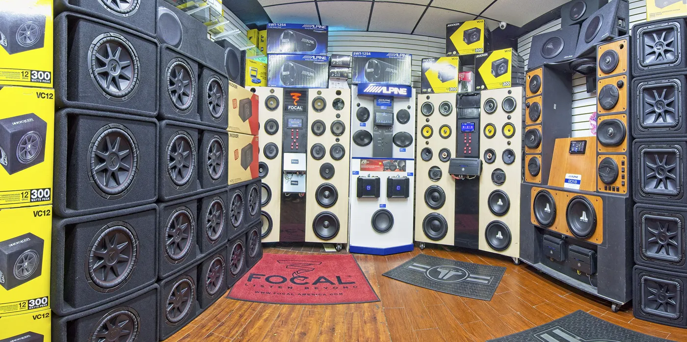 Kicker and JL Audio subwoofer boxes stacked beside the car speaker demo wall
